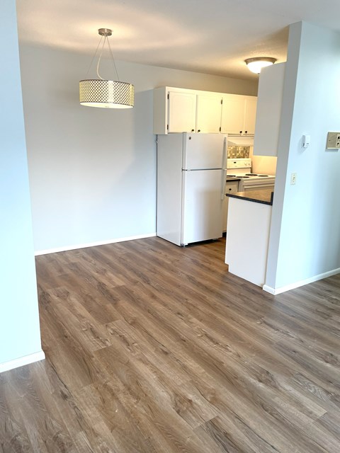 A kitchen with a white refrigerator and wooden floors.